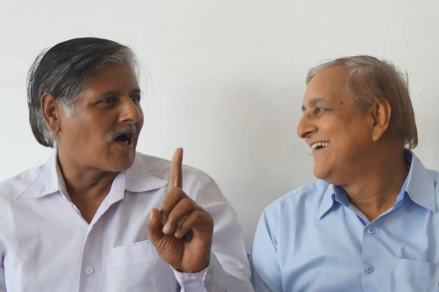 Two men in conversation, one making a point with a raised finger